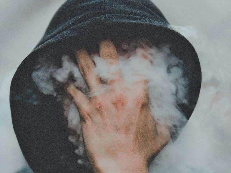 Guy covering his face while vaping because his throat stings