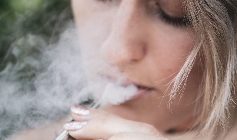 Girl inhaling e-cigarette vapour