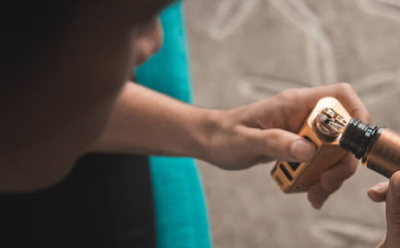 A boy pouring e-cigarette liquid into his e-cig