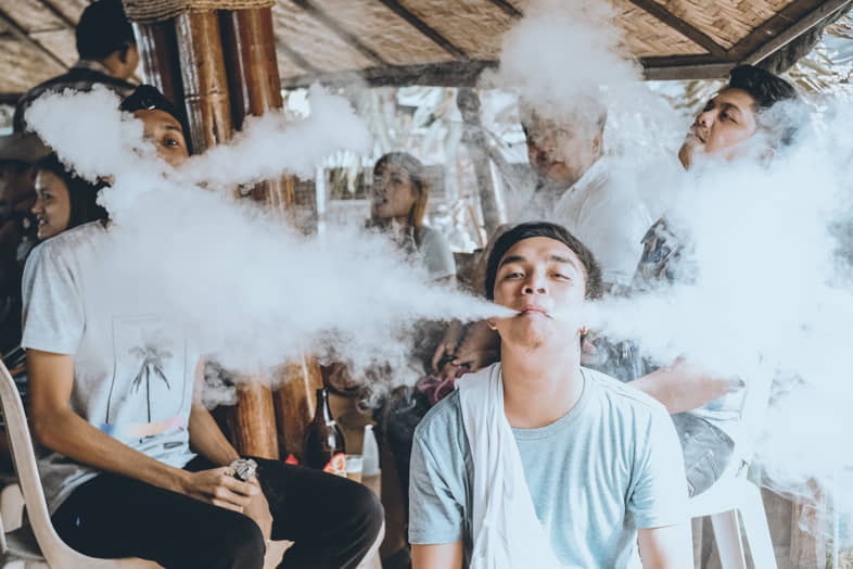 A group of young people cloud chasing, emitting large clouds of vapour