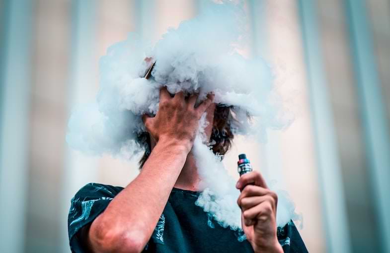 Boy using an e-cig and having e-cigarette liquid in his mouth